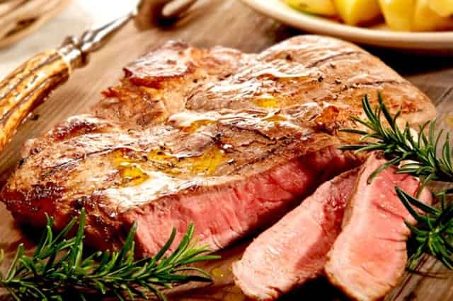 fetta di carne su un tagliere con rosmarino